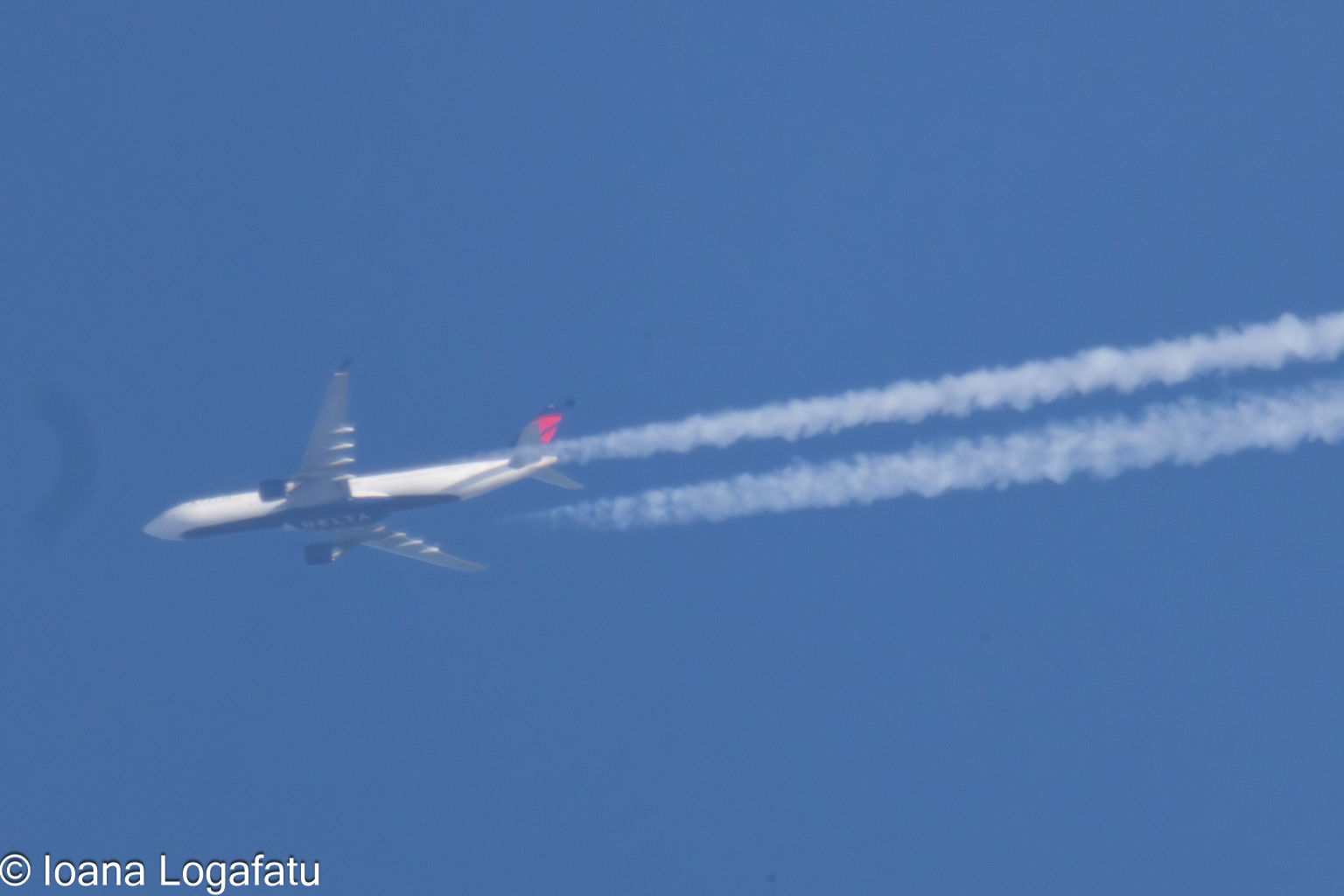 Contrails streak across the blue sky at midday